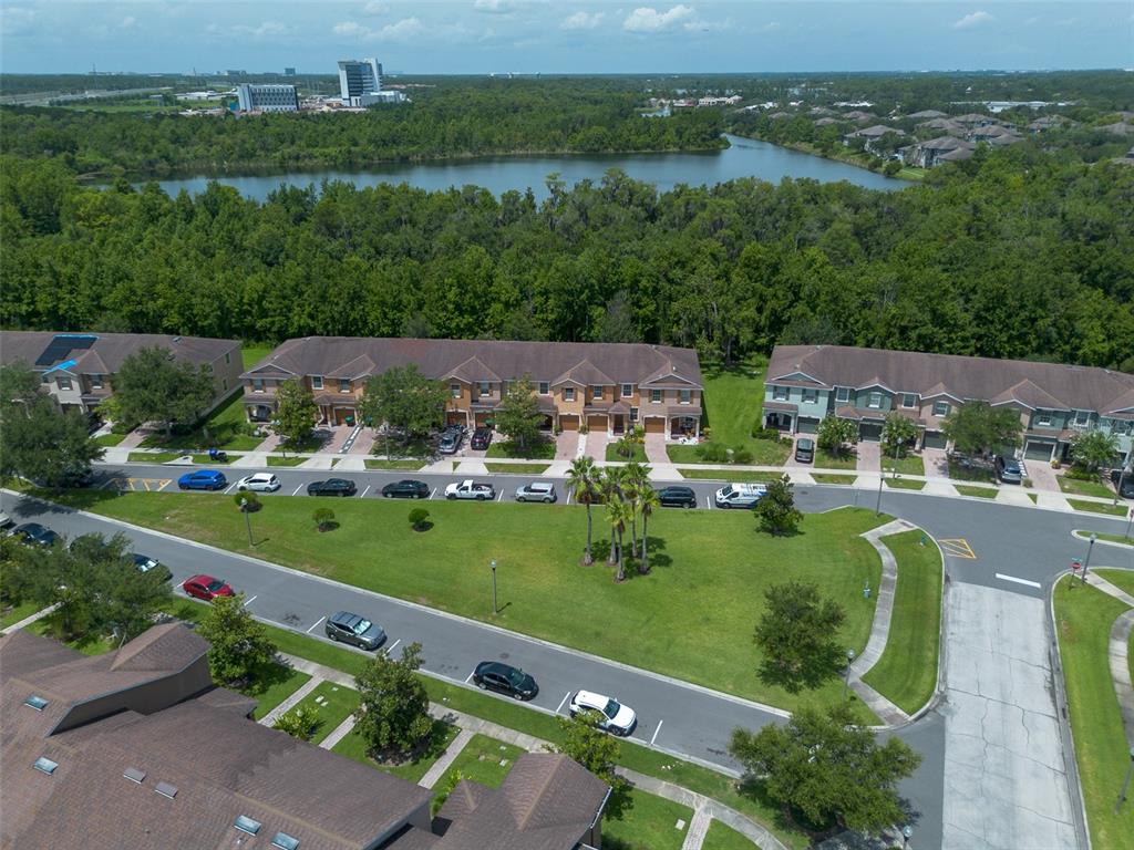 An aerial view shows townhouses, a central grassy area with parking, and a nearby lake — 11191 SAVANNAH LANDING CIRCLE, ORLANDO, FL