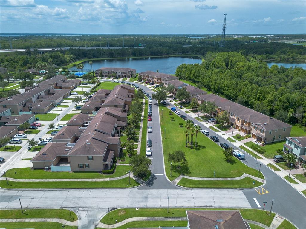 An aerial view shows a residential neighborhood with townhomes, a central street, and a lake — 11191 SAVANNAH LANDING CIRCLE, ORLANDO, FL