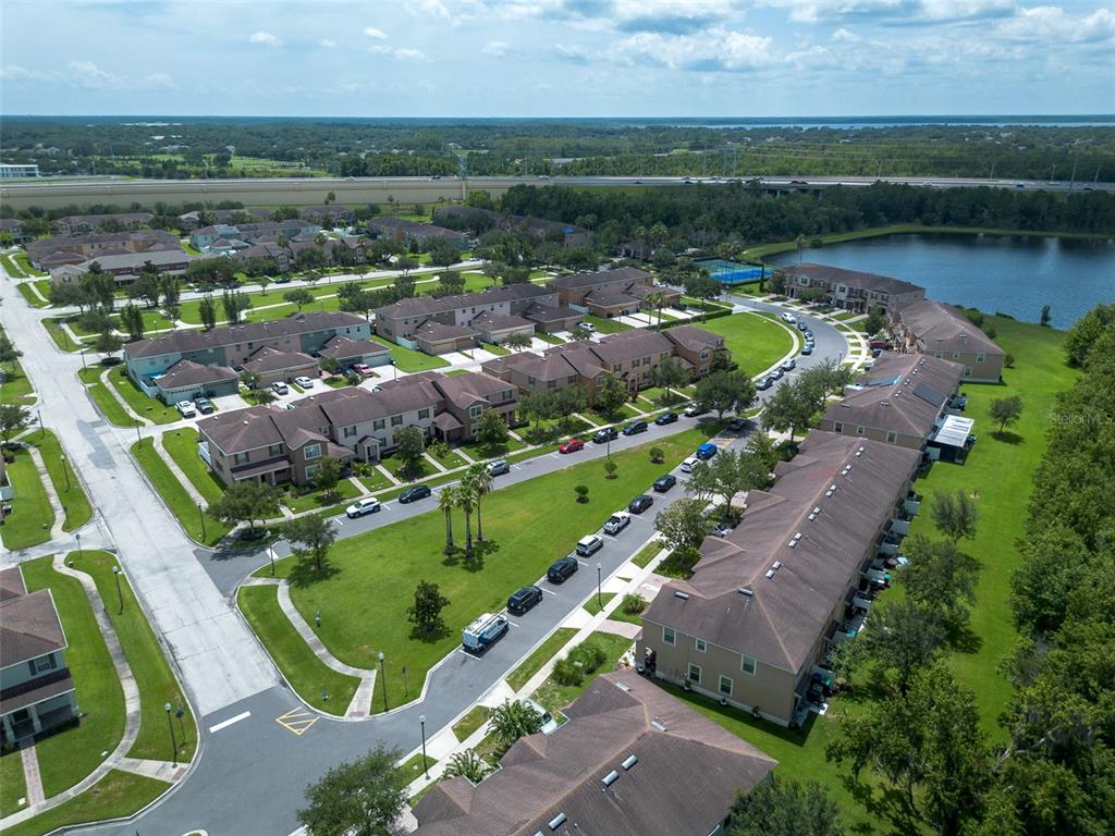 An aerial view shows a residential community with townhouses, a lake, and a nearby highway — 11191 SAVANNAH LANDING CIRCLE, ORLANDO, FL