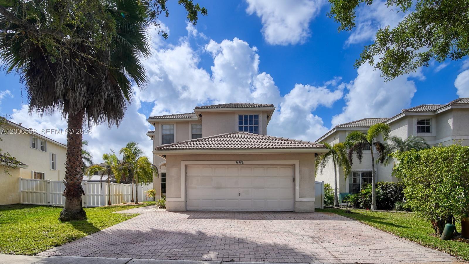 A two-story house with a beige stucco exterior and a tiled roof features a garage — 16388 SW 28th St, Miramar FL 33027, MIRAMAR, FL