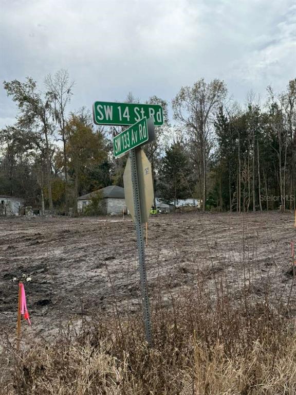 A street sign stands at the corner of a cleared, vacant lot with trees behind — 0000 Sw 14th ST ROAD, OCALA, FL