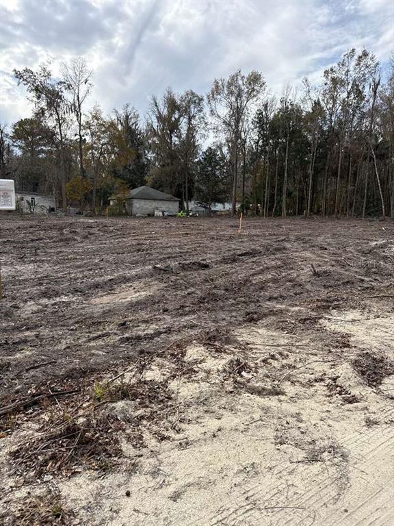 A cleared, dirt-covered vacant lot with trees in the background and a nearby house — 0000 Sw 14th ST ROAD, OCALA, FL