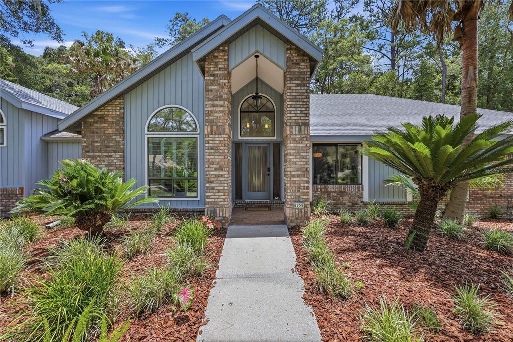 A single-story house with a brick and blue siding facade, arched windows, and a walkway — 8959 SW 44TH LANE, GAINESVILLE, FL