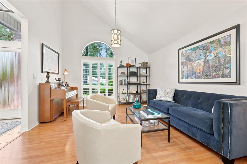 A living room features a blue sofa, two cream armchairs, a piano, and vaulted ceilings — 8959 SW 44TH LANE, GAINESVILLE, FL