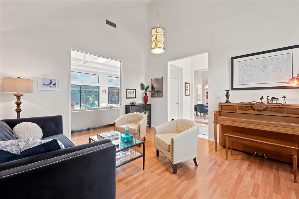 A living room features a dark blue sofa, two cream chairs, a piano, and hardwood floors — 8959 SW 44TH LANE, GAINESVILLE, FL