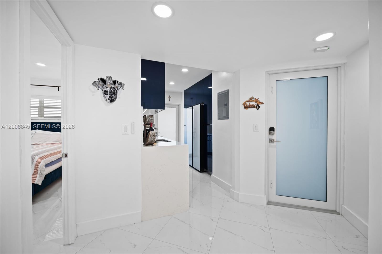 A white-tiled entryway leads to a kitchen with dark blue cabinets and a glass door — 710 N Ocean Blvd # 1010, Pompano Beach FL 33062, POMPANO BEACH, FL