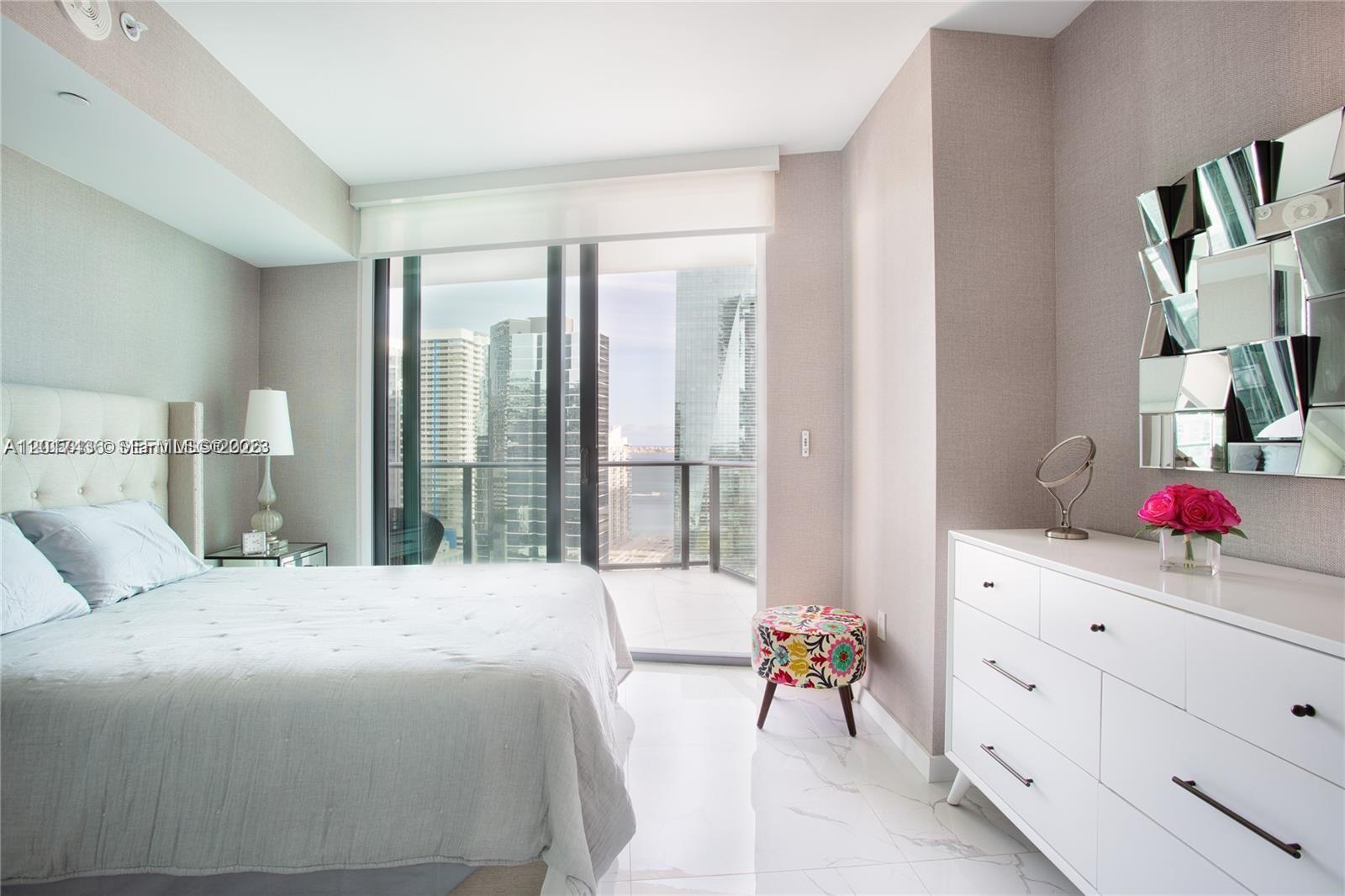 A modern bedroom features a white bed, a white dresser, and a balcony with city views — 1300 S Miami Ave # 2104, Miami FL 33130, MIAMI, FL