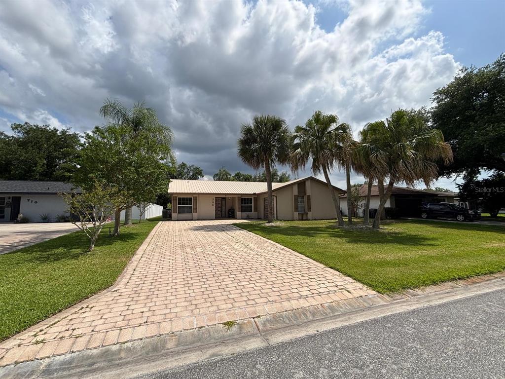 A single-story house with a paved driveway and palm trees in the front yard — 708 DUFFER LANE, KISSIMMEE, FL
