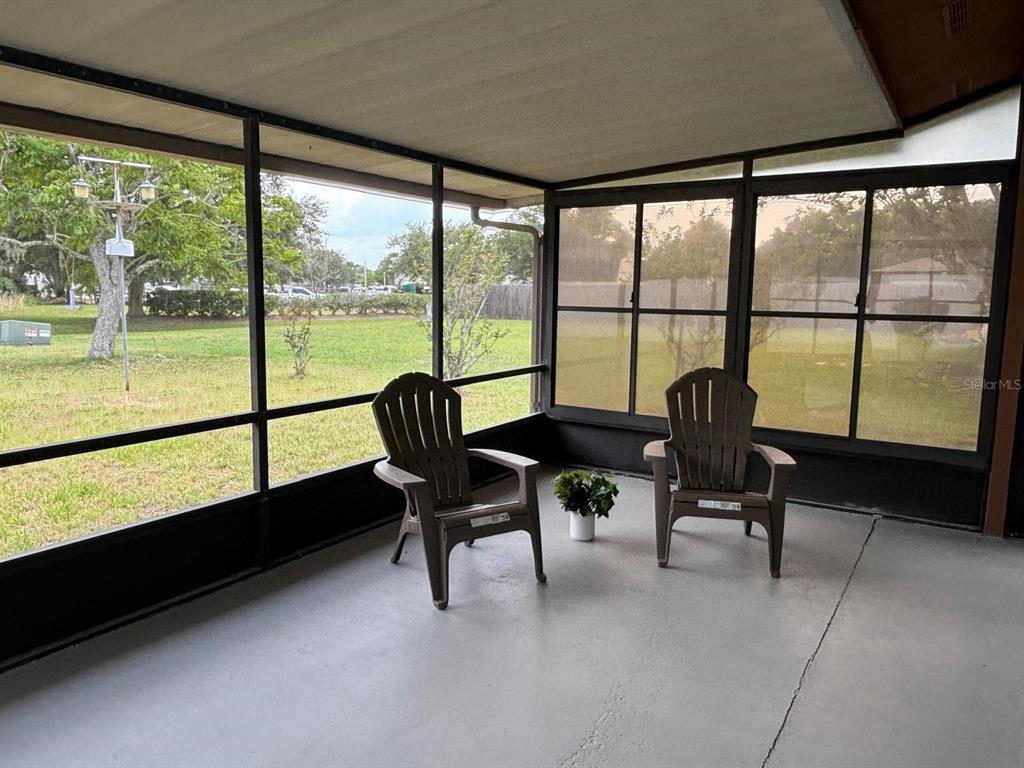 A screened-in porch features a concrete floor, two plastic chairs, and views of a yard — 708 DUFFER LANE, KISSIMMEE, FL