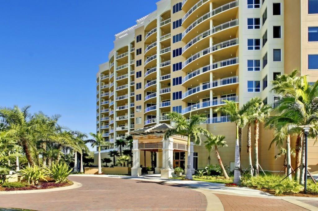 A multi-story residential building with balconies and a covered entrance driveway surrounded by palm trees — 1300 BENJAMIN FRANKLIN DRIVE UNIT 809, SARASOTA, FL
