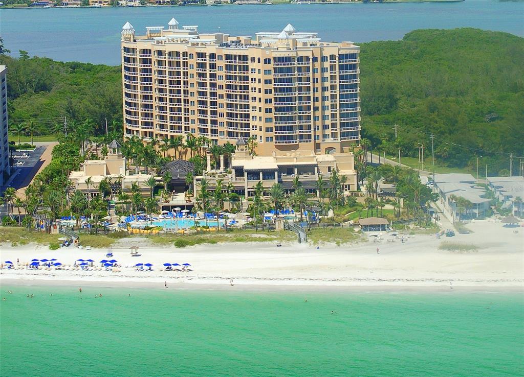 An aerial view of a large beachfront hotel with a pool and surrounding tropical landscaping — 1300 BENJAMIN FRANKLIN DRIVE UNIT 809, SARASOTA, FL