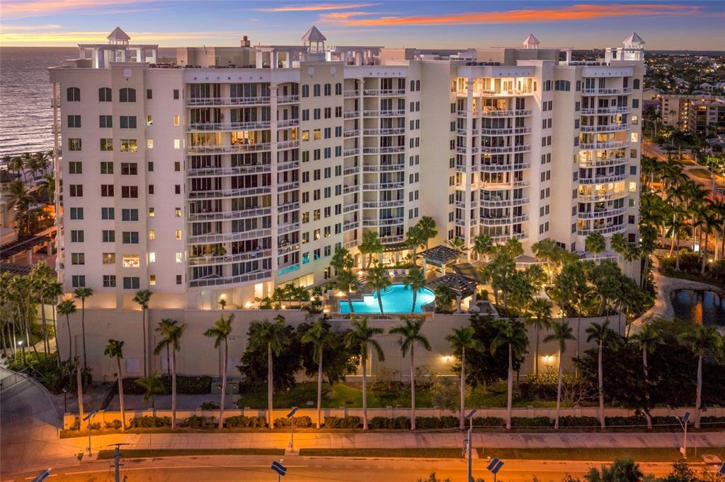 An aerial view of a large beachfront condominium complex with a pool and palm trees — 1300 BENJAMIN FRANKLIN DRIVE UNIT 809, SARASOTA, FL