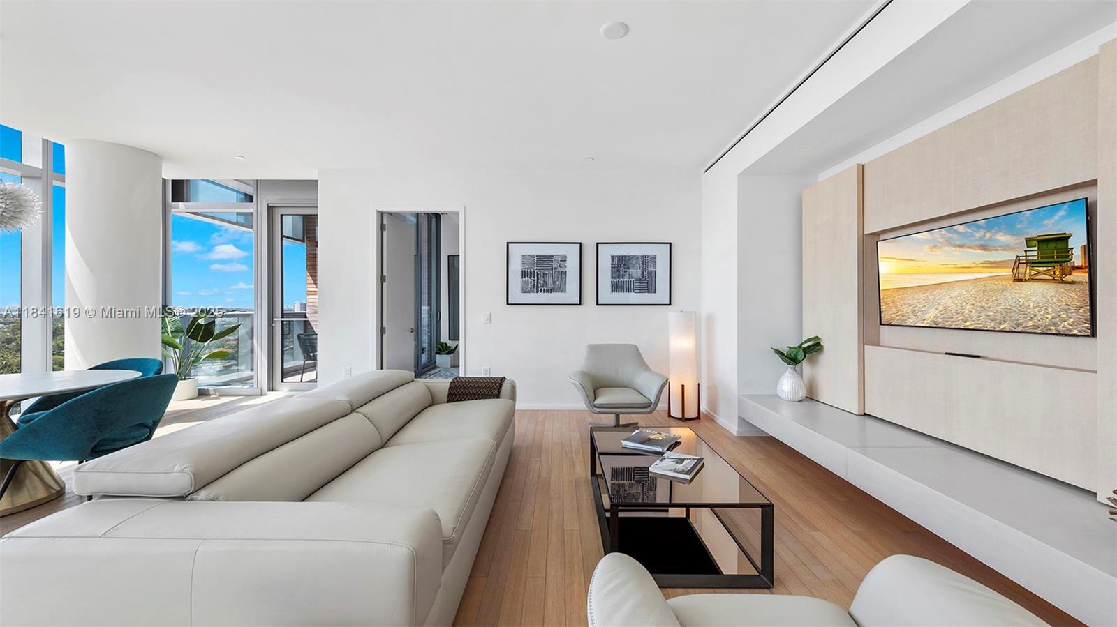A modern living room features a white leather sofa, glass coffee table, and wall-mounted television — 2901 Collins Ave # 1403, Miami Beach FL 33140, MIAMI BEACH, FL