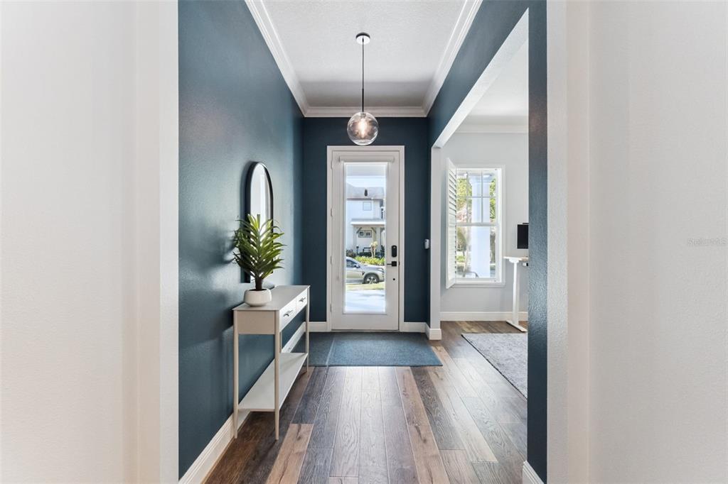 A foyer features dark blue walls, wood-look flooring, a glass pendant light, and a console table — 8257 LOWER PERSE CIRCLE, ORLANDO, FL