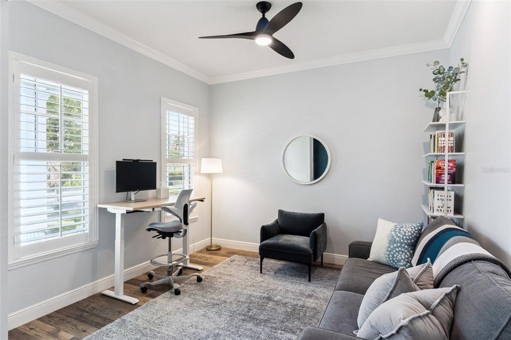 A home office features a standing desk, a grey sofa, a chair, and a bookshelf — 8257 LOWER PERSE CIRCLE, ORLANDO, FL
