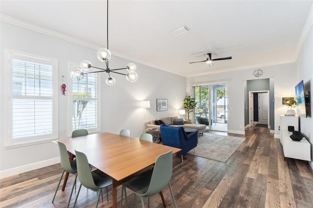 A dining area with a modern chandelier flows into a living room with wood-look flooring — 8257 LOWER PERSE CIRCLE, ORLANDO, FL