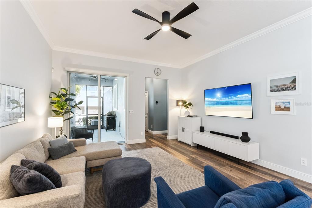 A living room features a sectional sofa, blue armchair, wall-mounted television, and sliding glass doors — 8257 LOWER PERSE CIRCLE, ORLANDO, FL