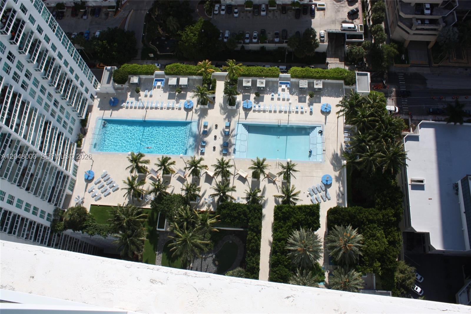 An aerial view shows two swimming pools surrounded by lounge chairs and palm trees — 951 Brickell Ave # 4006, Miami FL 33131, MIAMI, FL
