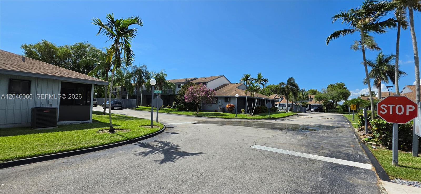 A paved road leads through a residential complex with palm trees and a stop sign — 1652 N 14th Ter # 1652, Hollywood FL 33020, HOLLYWOOD, FL