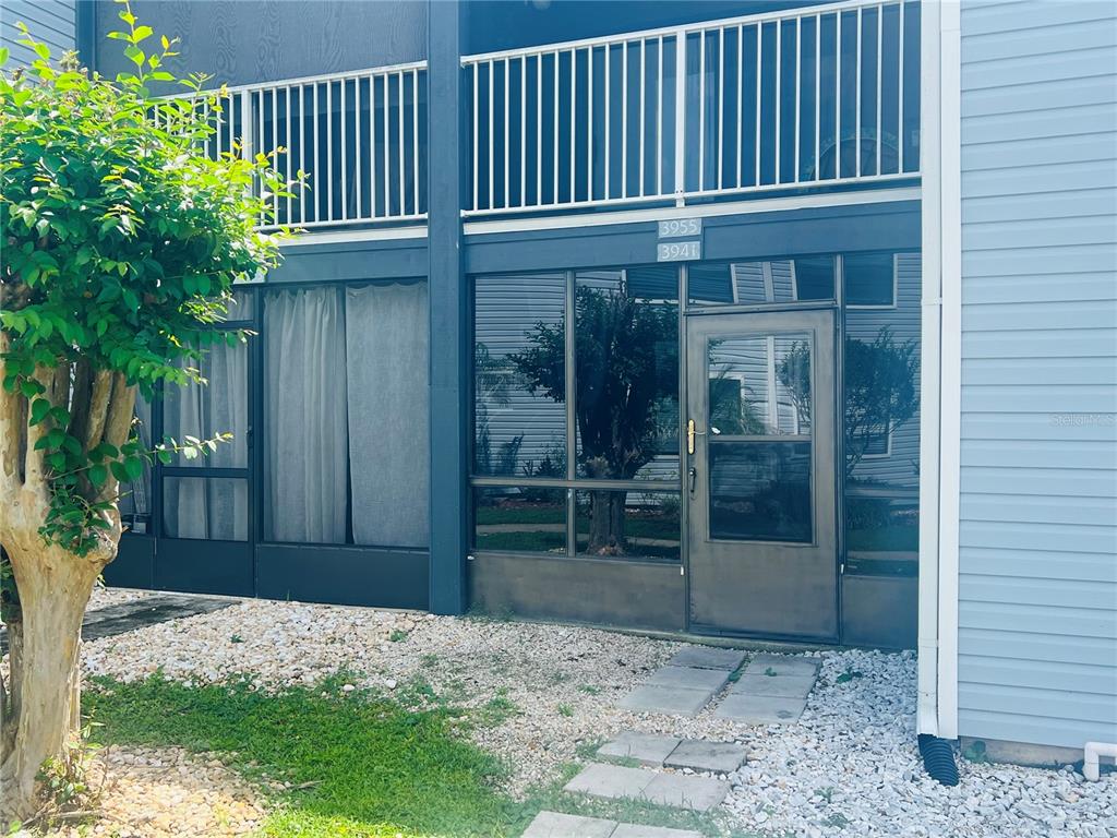 A ground-level patio entrance features a glass door, screened walls, and a stone walkway — 3941 ATRIUM DRIVE UNIT L3, ORLANDO, FL