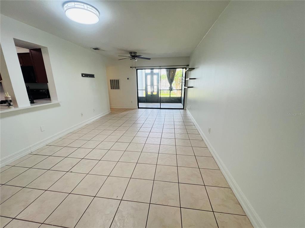 A tiled living area features a ceiling fan, wall shelving, and a sliding glass door — 3941 ATRIUM DRIVE UNIT L3, ORLANDO, FL