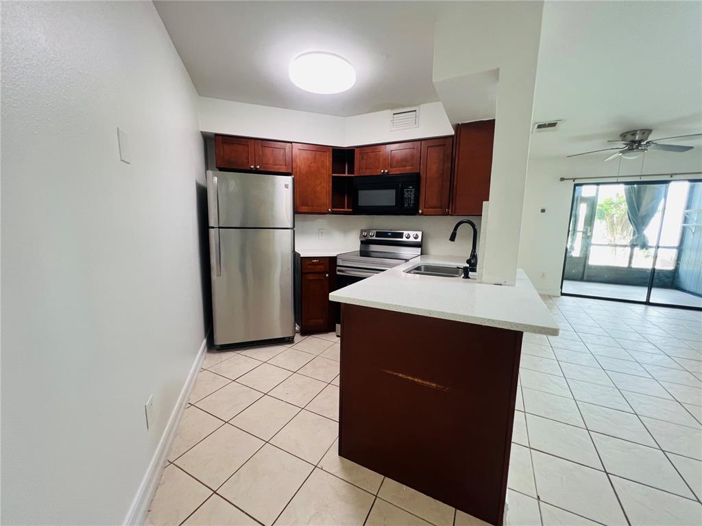 A kitchen with dark wood cabinets, stainless steel appliances, and a white countertop island — 3941 ATRIUM DRIVE UNIT L3, ORLANDO, FL