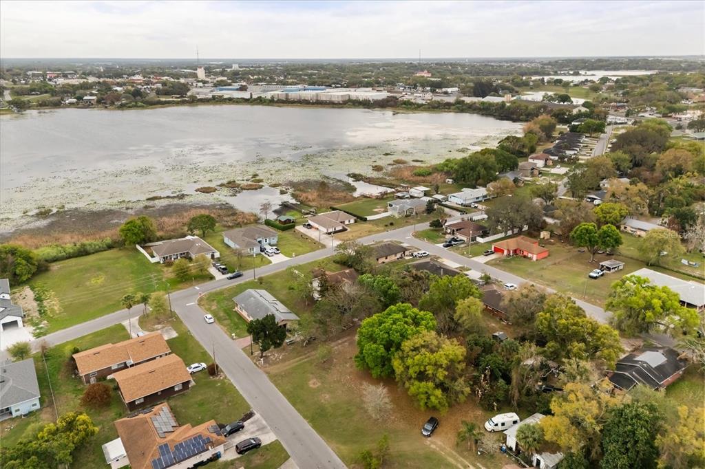 An aerial view shows a residential neighborhood situated along the edge of a large lake — 408 MCKAY DRIVE, HAINES CITY, FL