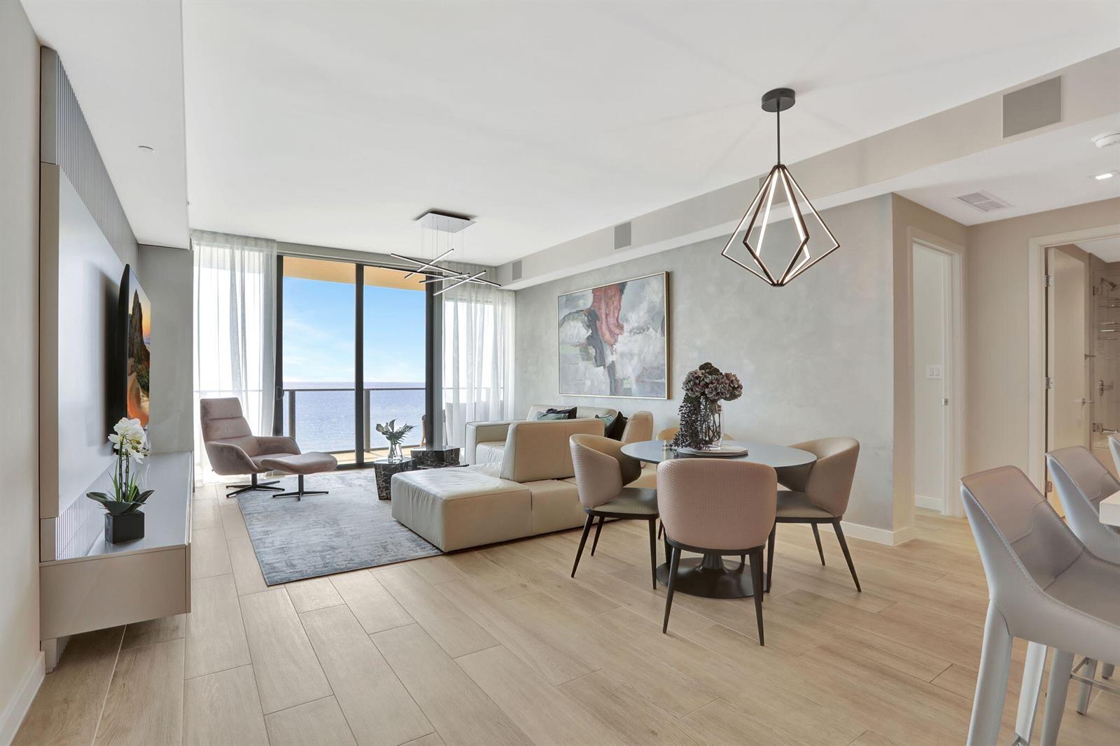 A modern living and dining area features light wood floors, ocean views, and contemporary furniture — 1116 N Ocean Boulevard # 1102, Pompano Beach FL 33062, POMPANO BEACH, FL