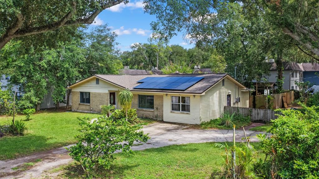 A single-story house with solar panels on the roof, a concrete driveway, and surrounding trees — 201 MASON STREET, BRANDON, FL