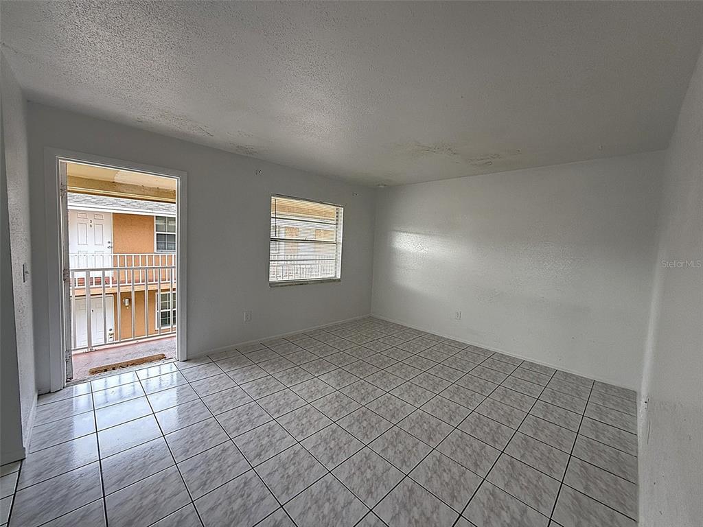 An empty room with white walls, tiled floors, a window, and a door to a balcony — 720 MICHIGAN COURT UNIT 4, ST CLOUD, FL