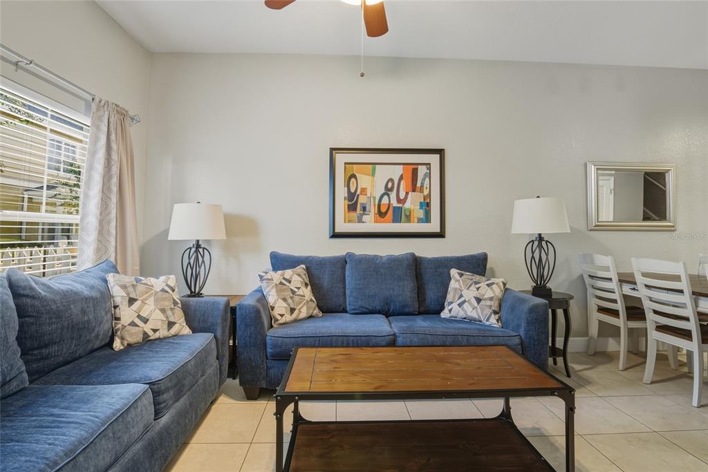 A living room features blue sofas, a wooden coffee table, and a dining area nearby — 2610 LODI CIRCLE UNIT 106, KISSIMMEE, FL