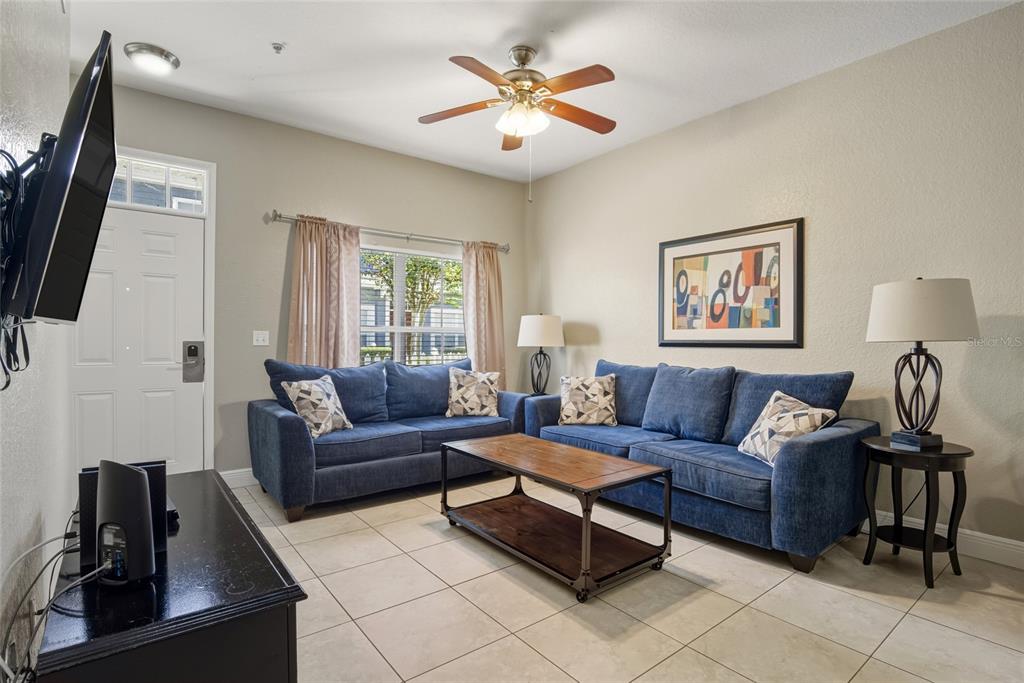 A living room features two blue sofas, a wooden coffee table, and tile flooring — 2610 LODI CIRCLE UNIT 106, KISSIMMEE, FL