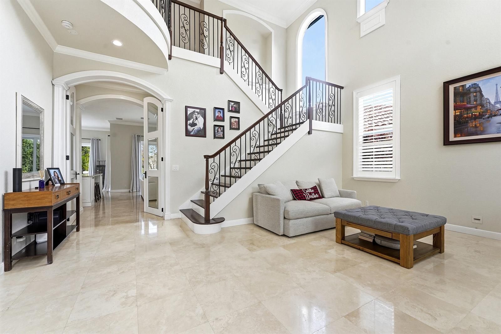 A bright foyer features a grand staircase, tile flooring, a small sofa, and an ottoman — 5038 NW 24th Circle, Boca Raton FL 33431, BOCA RATON, FL