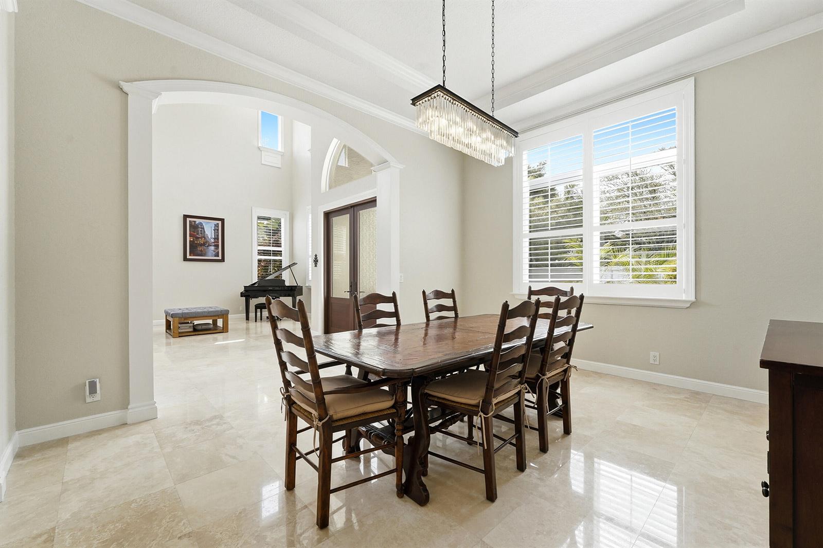 A dining room with a wooden table, six chairs, a crystal chandelier, and marble floors — 5038 NW 24th Circle, Boca Raton FL 33431, BOCA RATON, FL