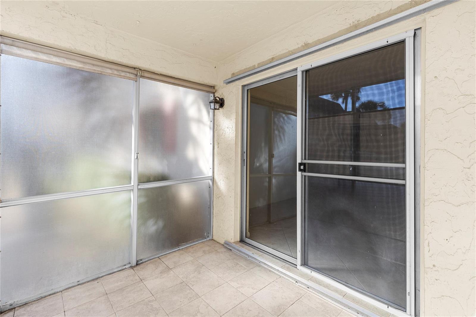 A tiled patio features a sliding glass door and frosted screen panels — 101 E Mcnab Road # 112, Pompano Beach FL 33060, POMPANO BEACH, FL