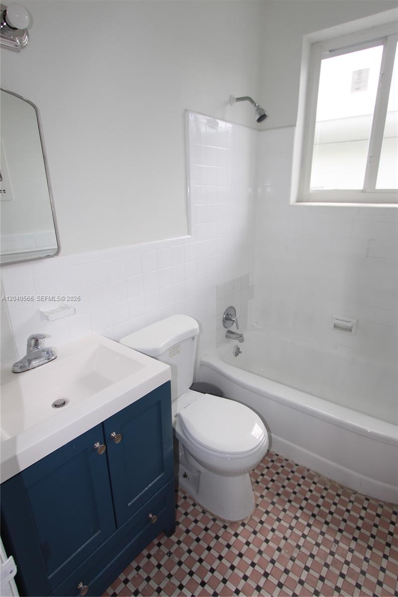 A bathroom features a blue vanity, white toilet, and a bathtub with white tile walls — 1115 Euclid Ave # 11, Miami Beach FL 33139, MIAMI BEACH, FL