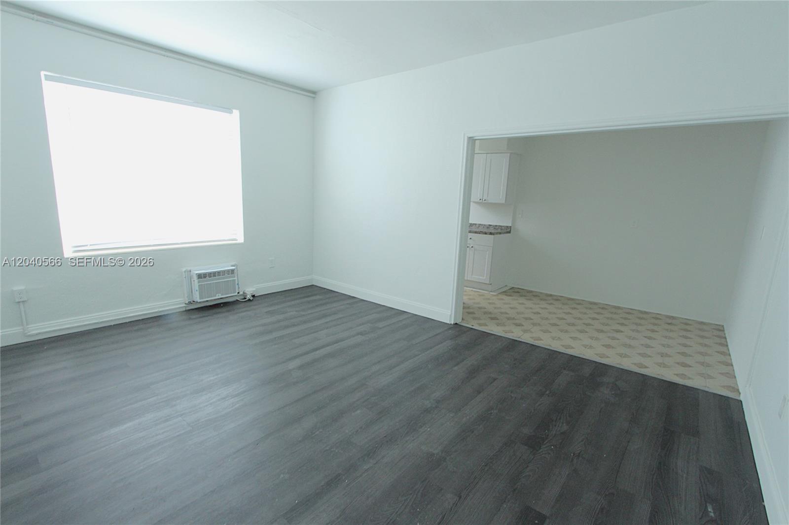 A living room with dark wood-look flooring connects to a kitchen with tiled floors — 1115 Euclid Ave # 11, Miami Beach FL 33139, MIAMI BEACH, FL