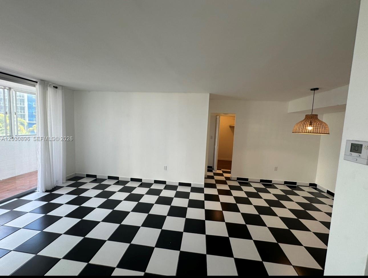 An empty room features black and white checkered tile flooring and a woven pendant light — 5055 NW 7th St # 409, Miami FL 33126, MIAMI, FL