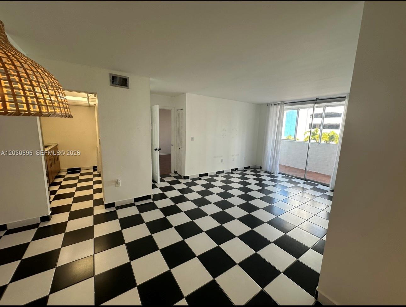 An interior room features black and white checkered tile flooring and a sliding glass door — 5055 NW 7th St # 409, Miami FL 33126, MIAMI, FL