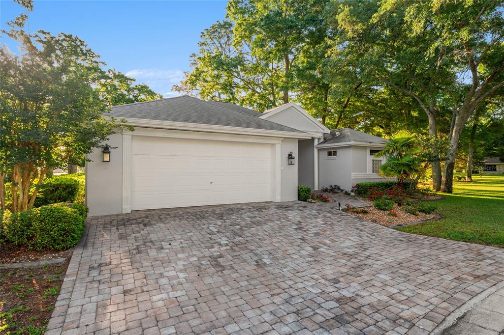 A single-story house with a white garage door and a paved driveway surrounded by trees — 10801 SW 71ST AVE, OCALA, FL