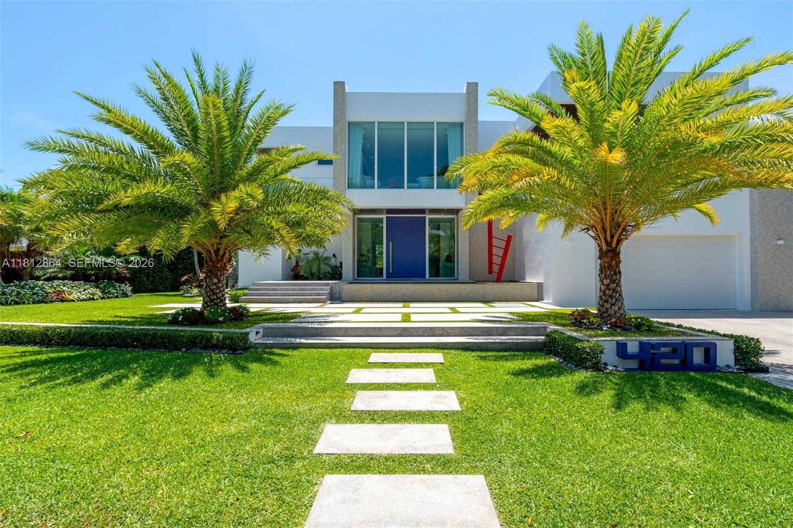 A modern two-story house features a blue front door, palm trees, and a concrete walkway — 420 Island Dr, Key Biscayne FL 33149, KEY BISCAYNE, FL