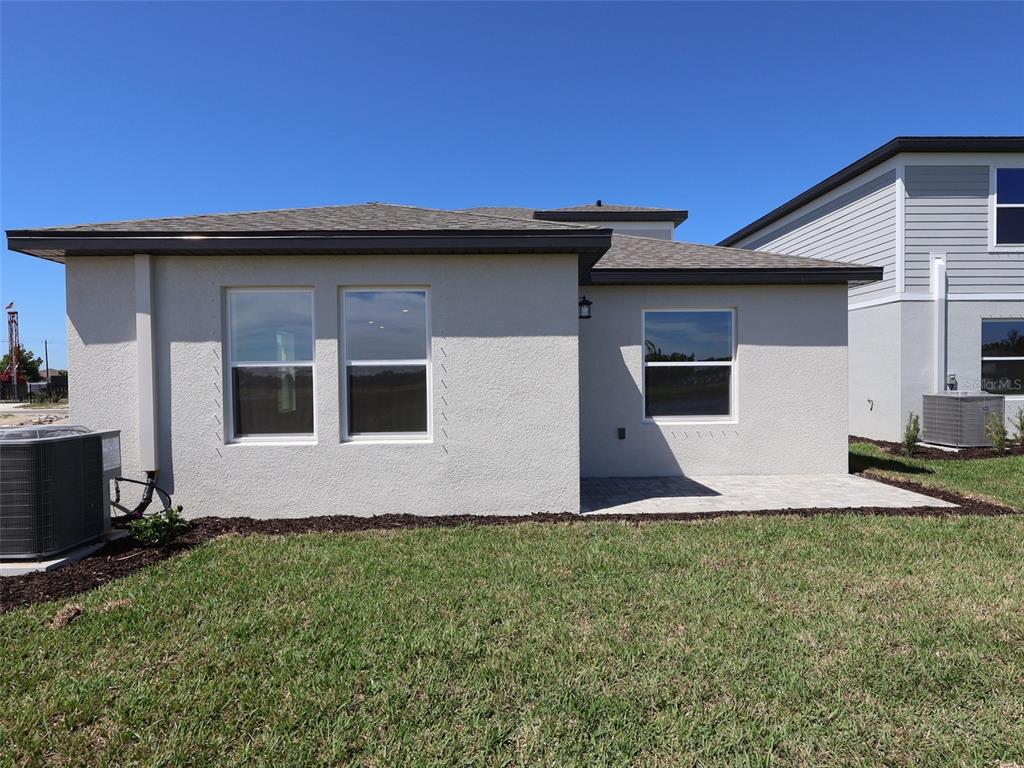 The exterior rear view of a single-story house features a patio and a grass lawn — 9014 OPTIMIST WAY, PALMETTO, FL