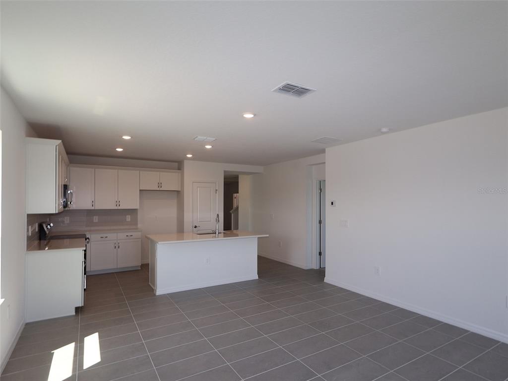 A kitchen with white cabinets, a central island, and gray tile flooring — 9014 OPTIMIST WAY, PALMETTO, FL