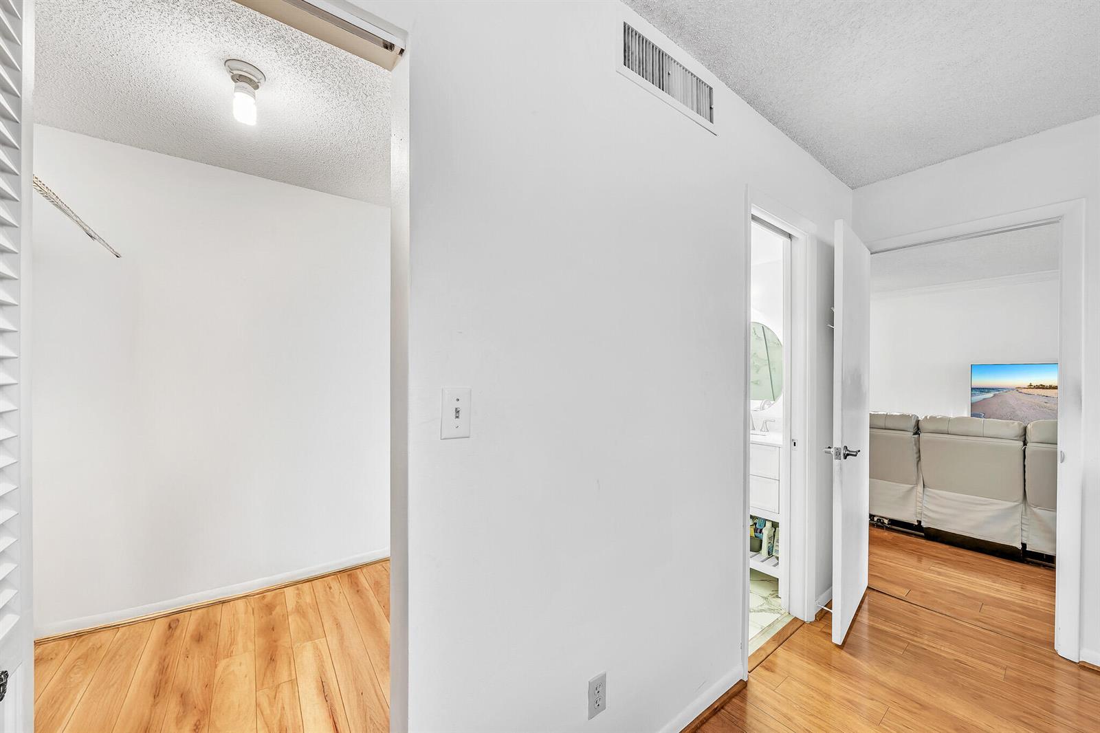 A hallway leads to a closet, a bathroom, and a living area with wood flooring — 5940 NW 64th Avenue Unit 101, Tamarac FL 33319, TAMARAC, FL