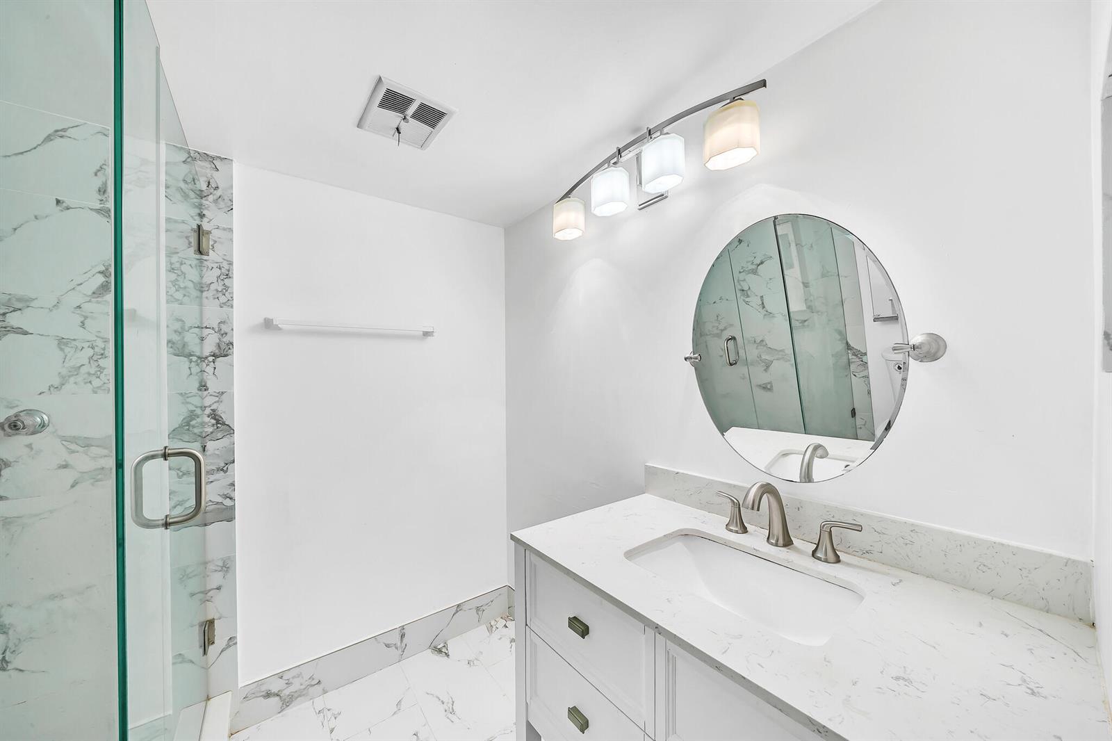 A modern bathroom features a white vanity with a marble countertop and a glass shower — 5940 NW 64th Avenue Unit 101, Tamarac FL 33319, TAMARAC, FL