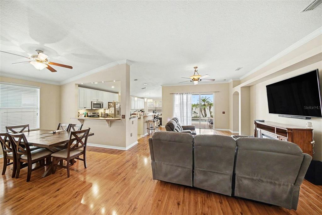An open-concept living and dining area features hardwood floors, a kitchen, and a sliding door — 215 FERN GULLEY DRIVE, SEFFNER, FL