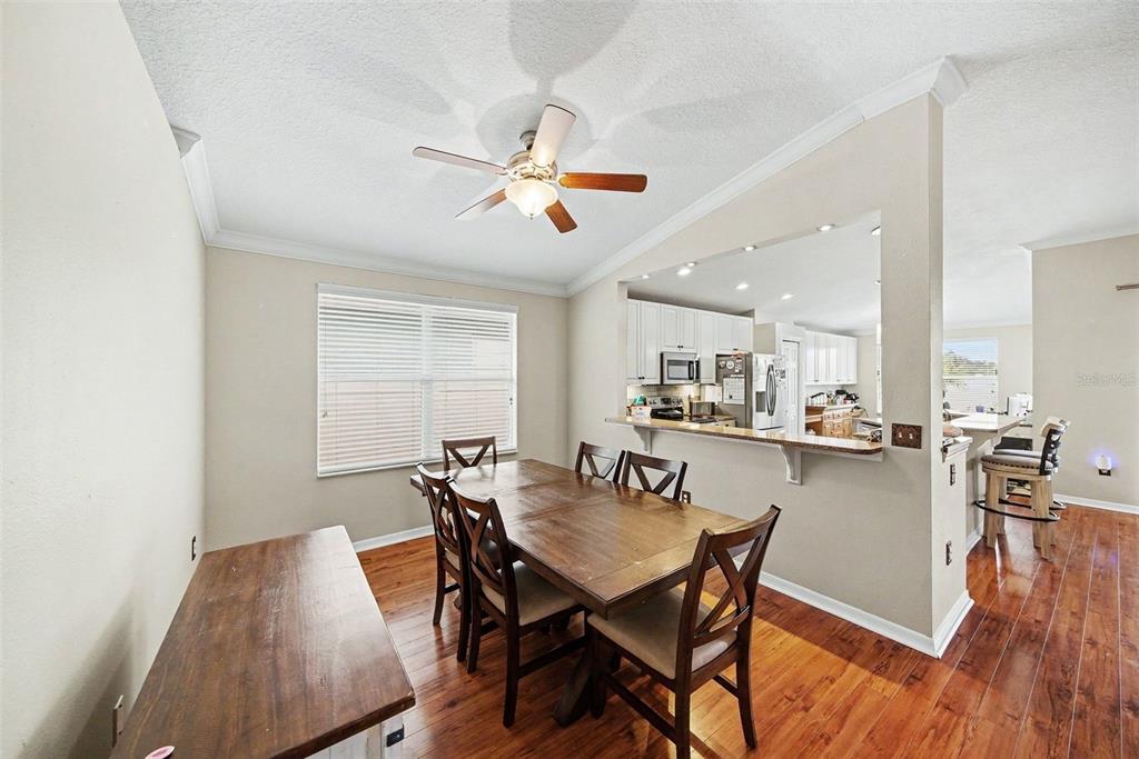 A dining room with a wooden table and chairs, adjacent to an open kitchen — 215 FERN GULLEY DRIVE, SEFFNER, FL