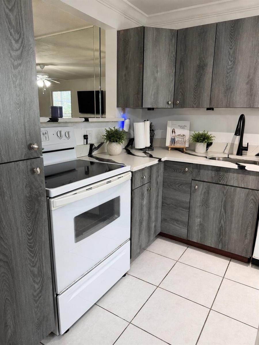 A kitchen features grey wood-grain cabinets, white appliances, and white countertops with black veining — 5961 NW 2nd Avenue # 108, Boca Raton FL 33487, BOCA RATON, FL