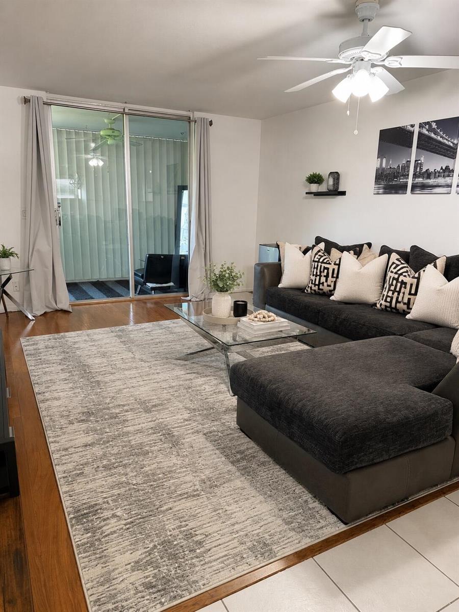 A living room features a dark sectional sofa, a glass coffee table, and a large rug — 5961 NW 2nd Avenue # 108, Boca Raton FL 33487, BOCA RATON, FL