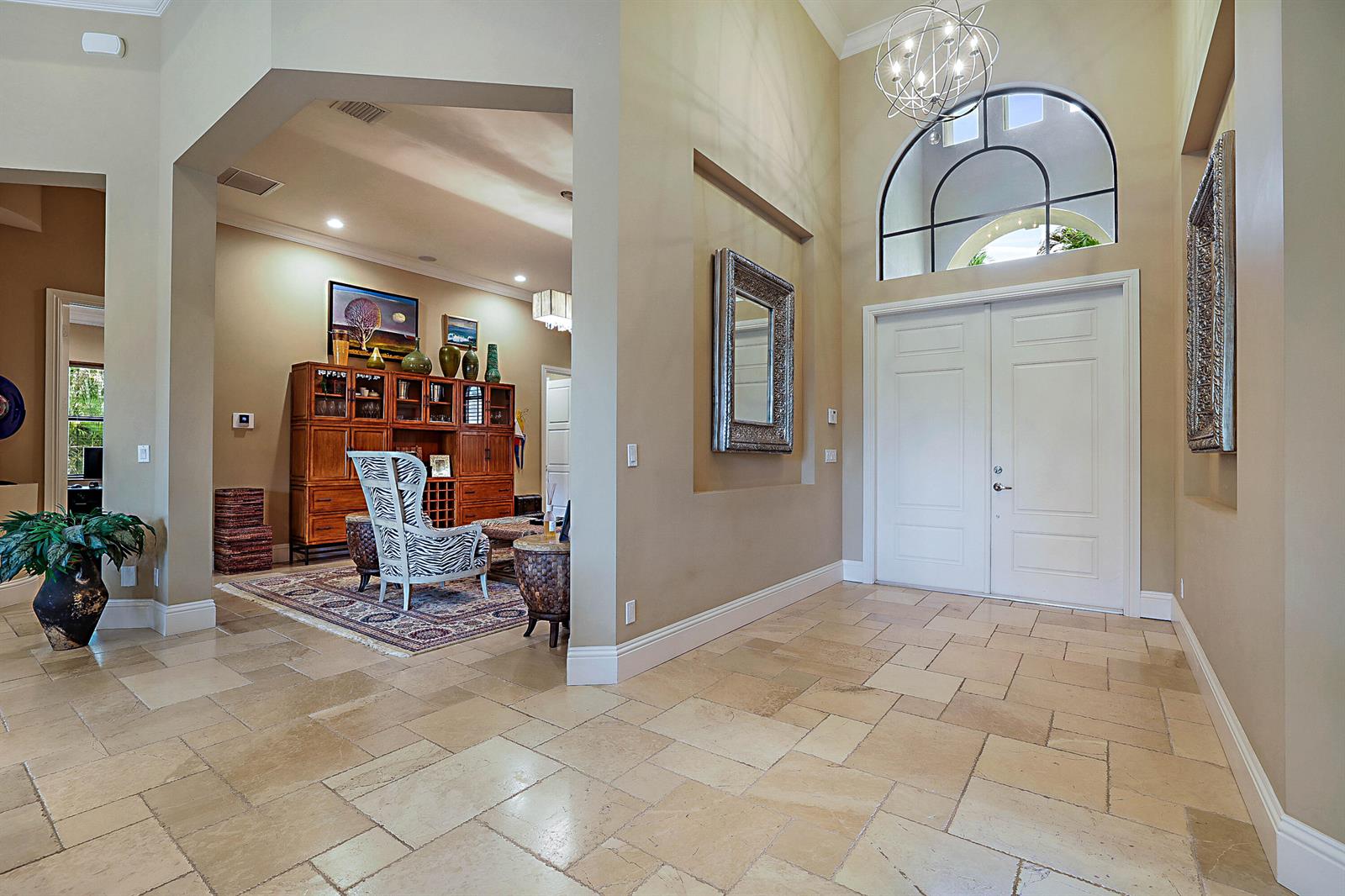 A spacious foyer with stone tile flooring leads into a living area with wooden cabinetry — 18337 SE Old Trail Drive W, Jupiter FL 33478, JUPITER, FL